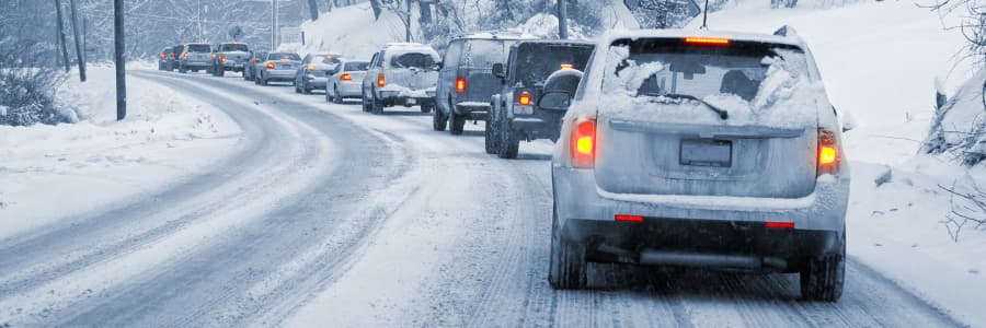 A line of cars on a winter road covered in snow.